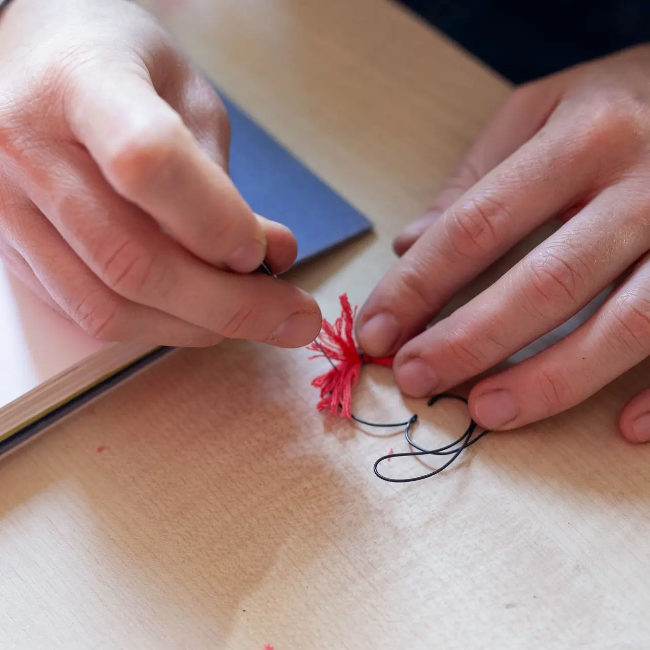 Photograpie de la fabrication du  pompon, etape de l'effilochage de la laine couleur tangerine 